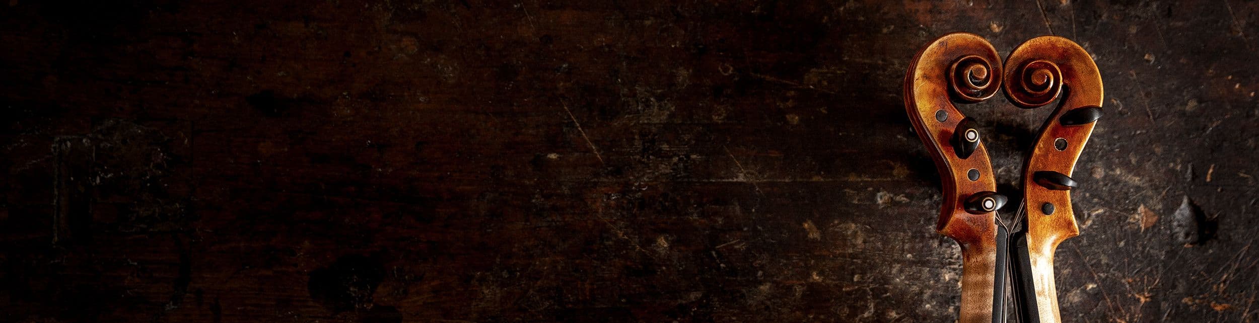 Auf einer alten Werkbank liegen zwei Geigenschnecken, die zusammen ein Herz formen.