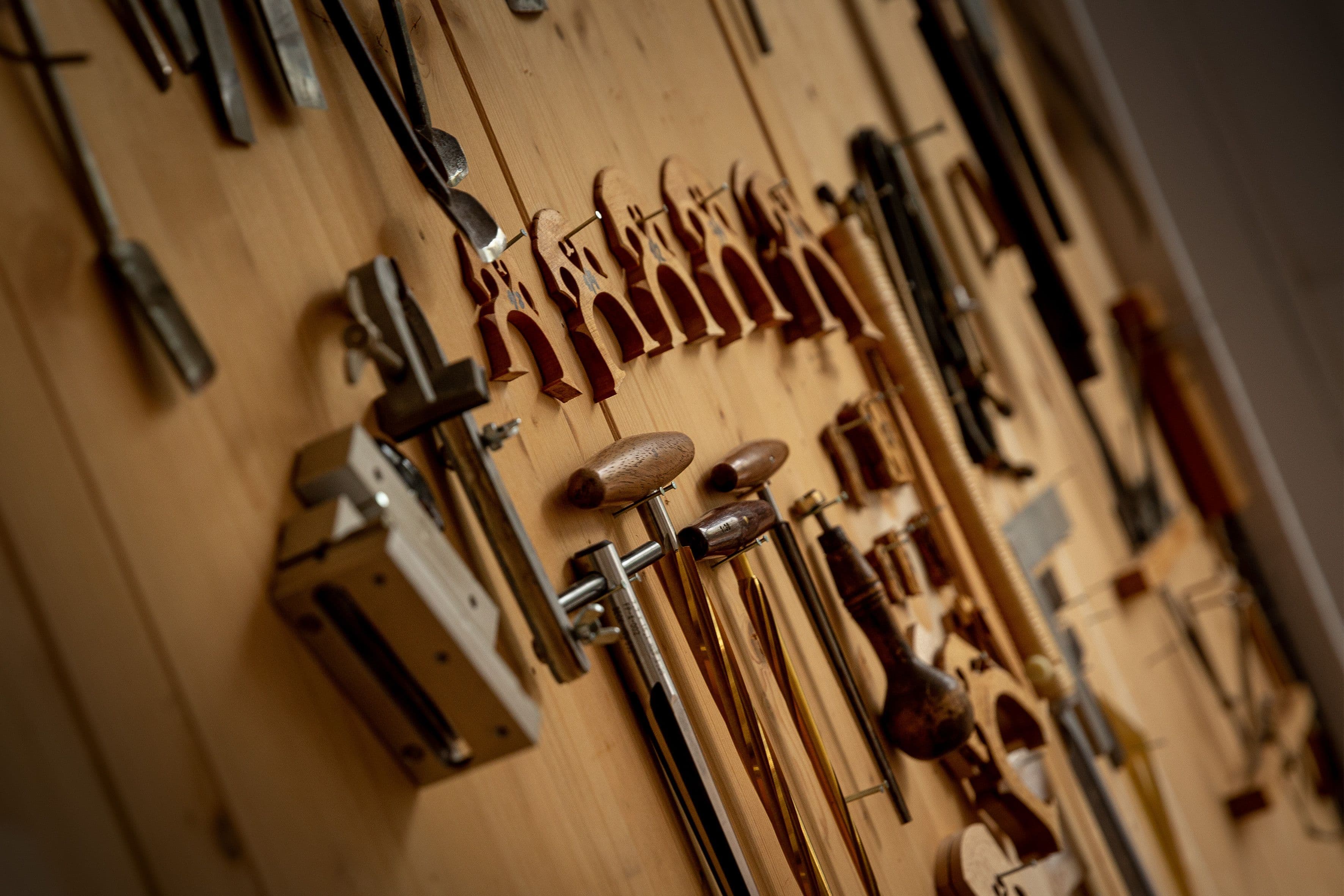 Eine Holzwand mit vielen verschiedenen Geigenbauwerkzeugen und Stegen