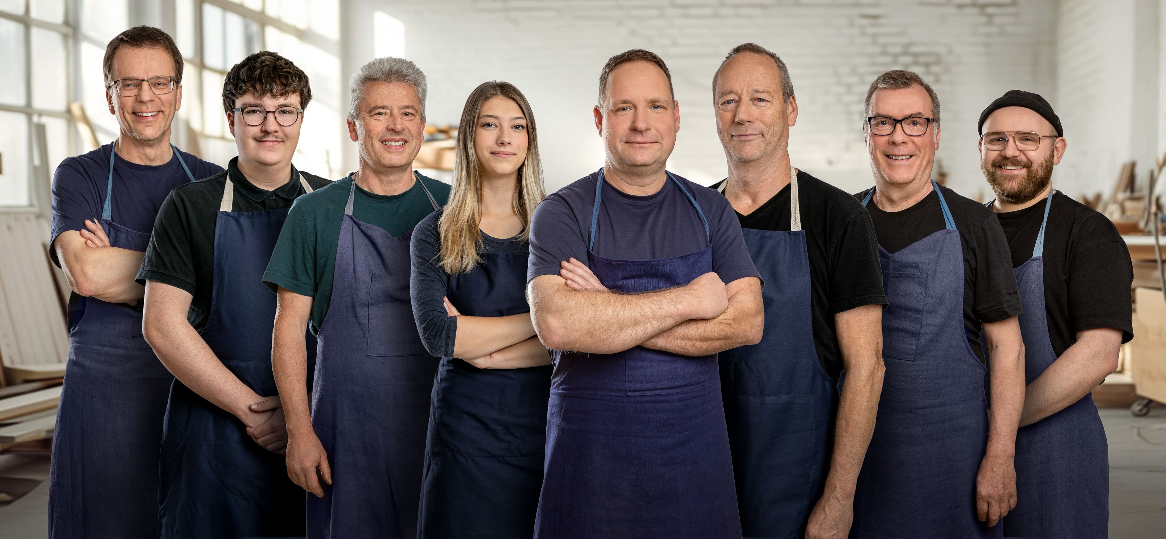 unsere acht Werkstattmitarbeiter*innen stehen nebeneinander und lächeln freundlich