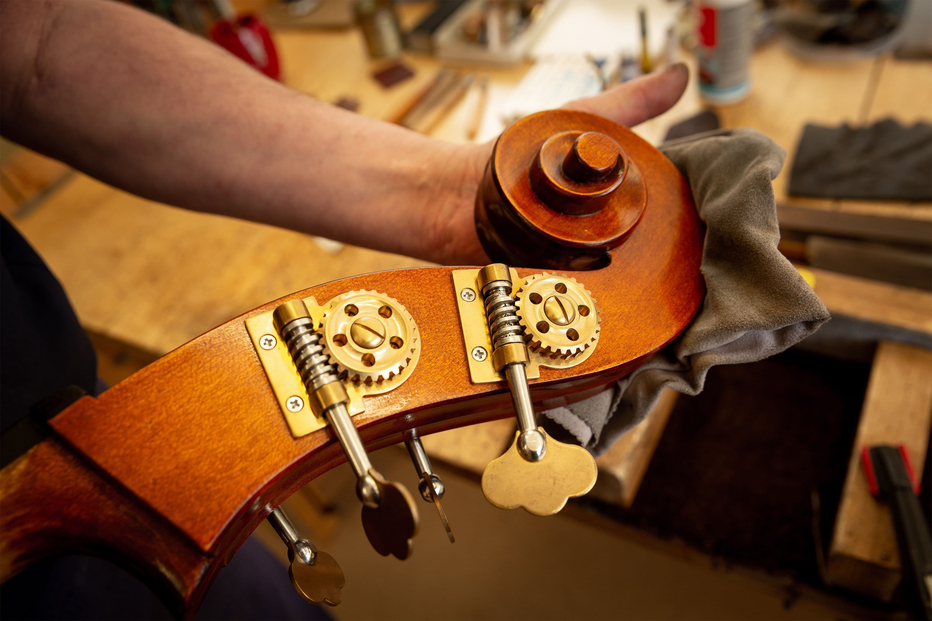 Jemand poliert mit einem Tuch die Schnecke eines großen Kontrabasses