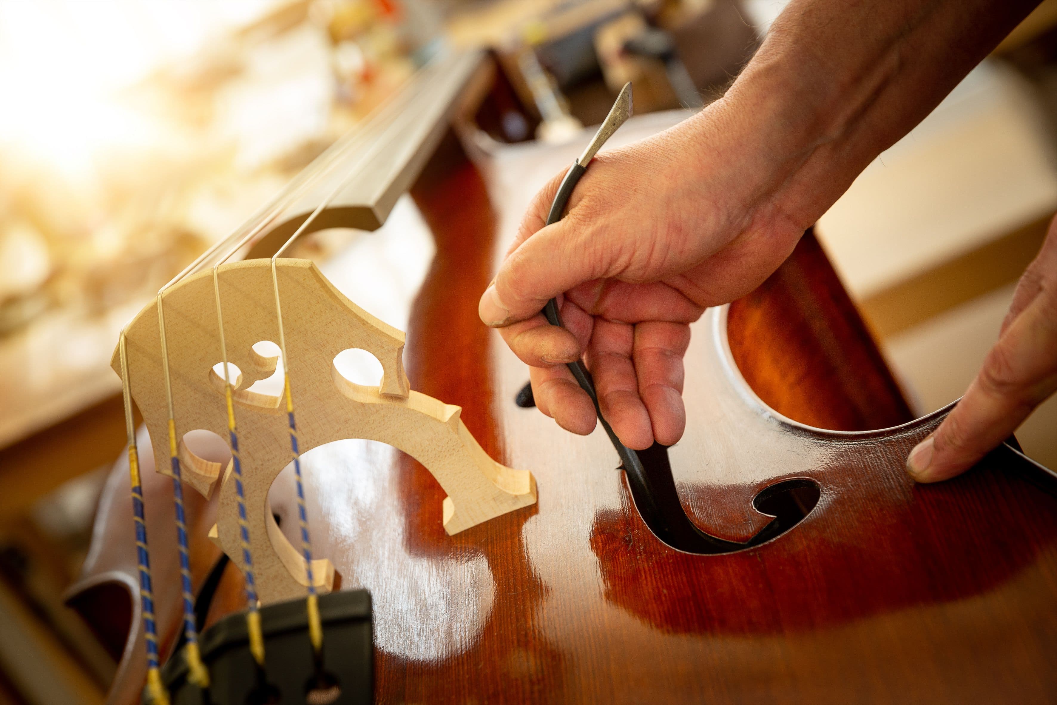 Jemand setzt mit einem Stimmsetzer die Stimme in einen Kontrabass