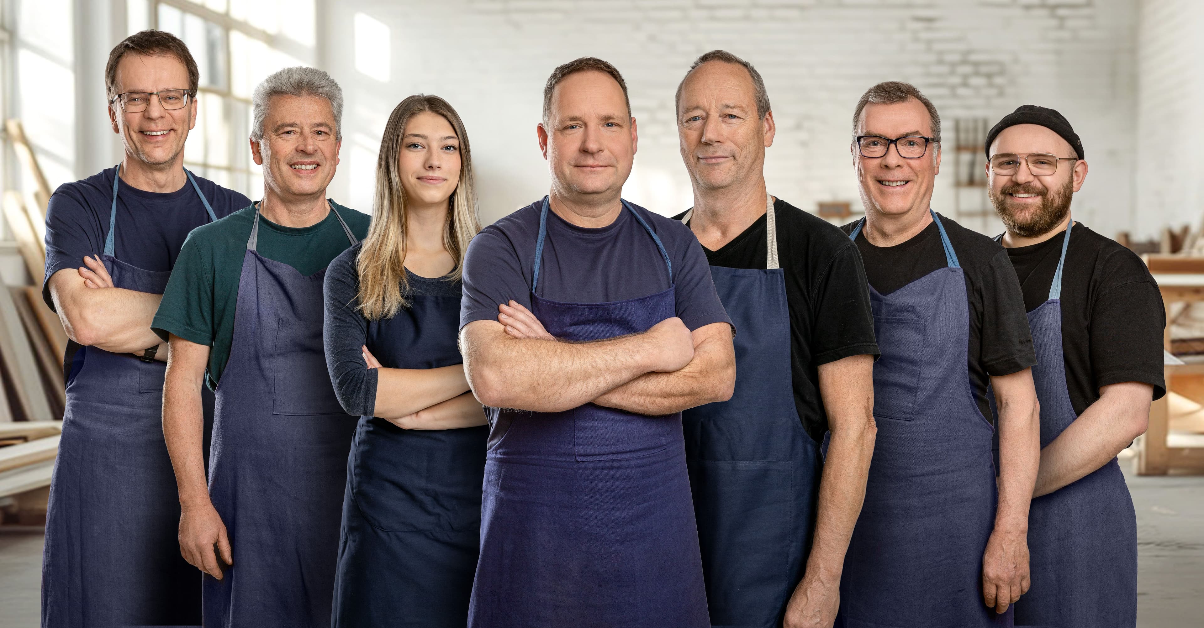 unsere acht Werkstattmitarbeiter*innen stehen nebeneinander und lächeln freundlich